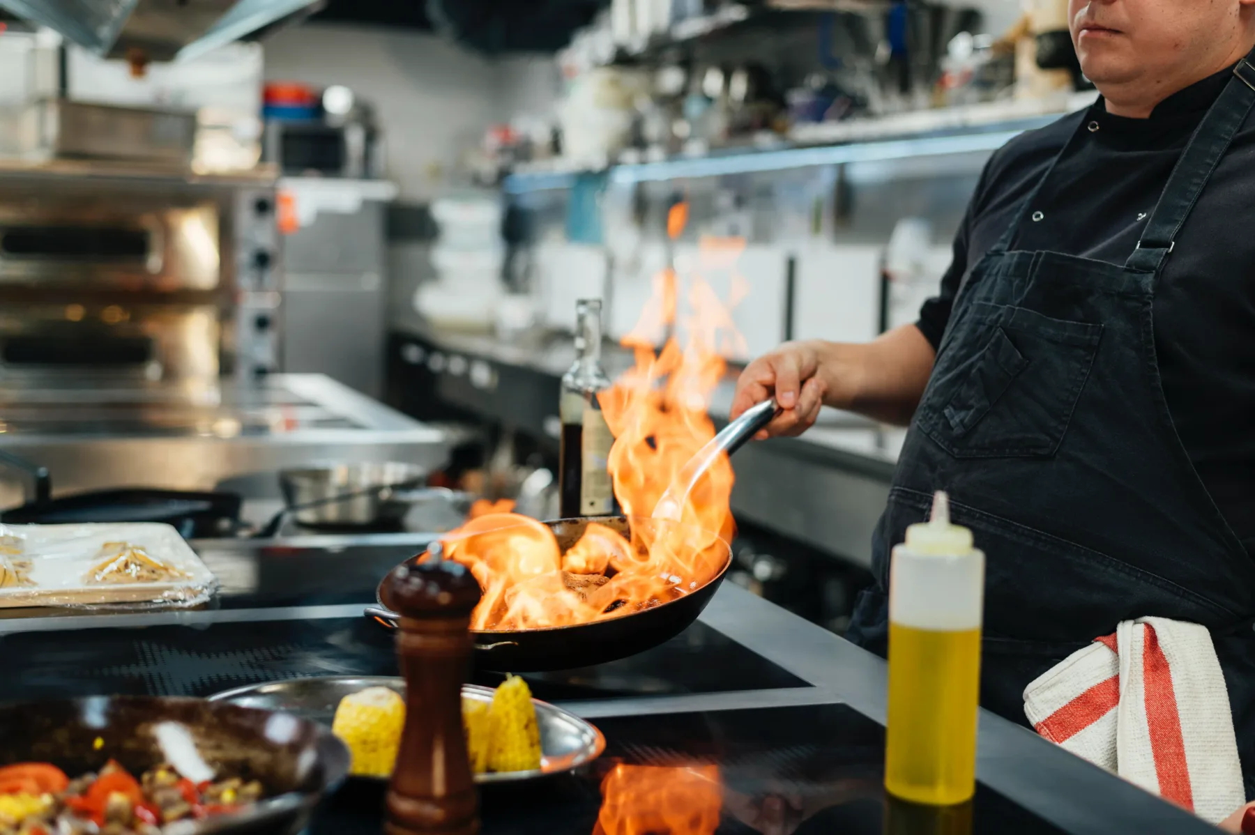 Cocinero preparando un pedido sobre una llama abierta en la cocina de un restaurante